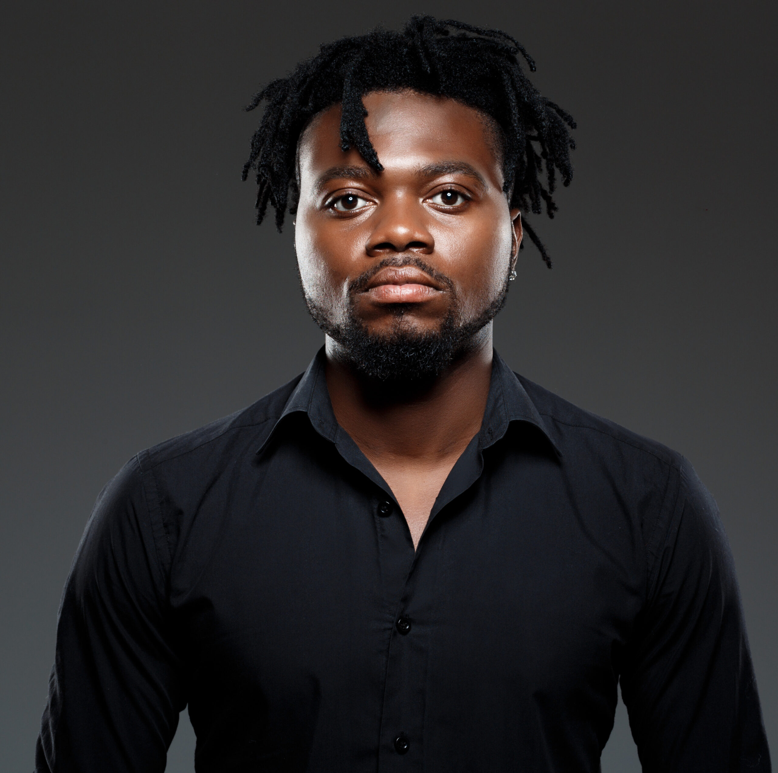 young successful african businessman posing over dark background. edited scaled.jpg